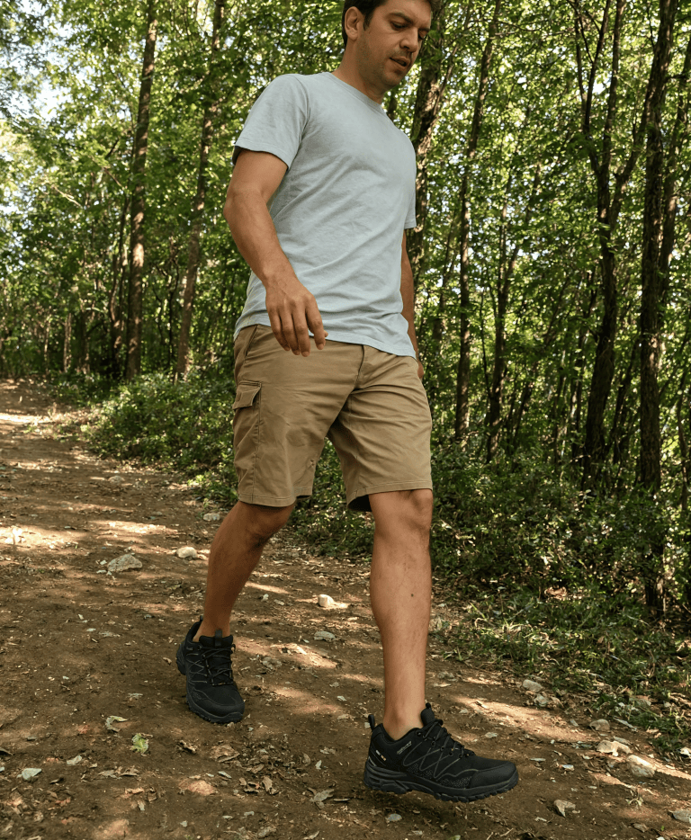 Mężczyzna idący w butach trekkingowych American Club przez las
