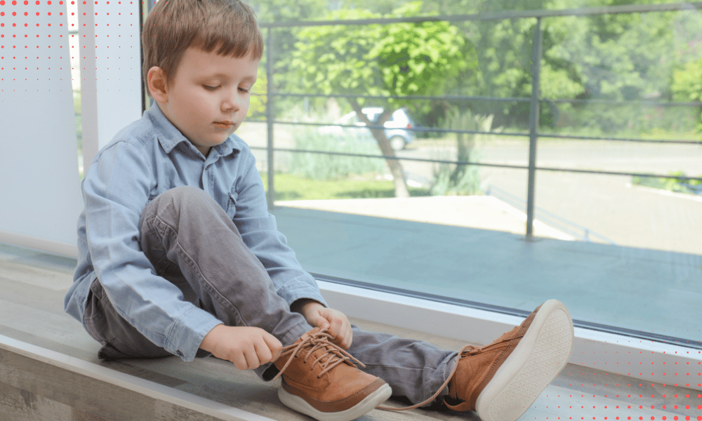 Dziecko siedzące na podłodze i samodzielnie zakładające prawidłowo dobrane buty.